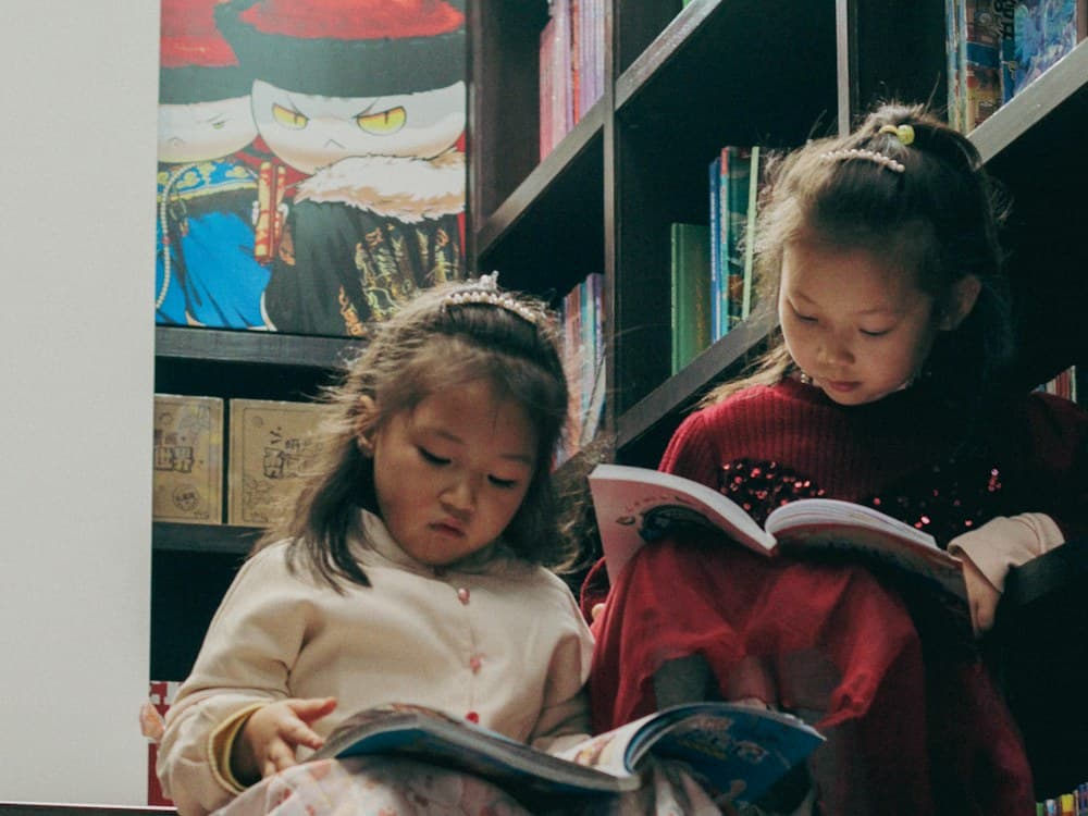 Dos niñas leyendo libros en el rincón de lectura