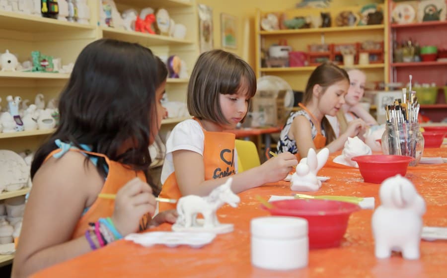 Niñas pintando figuras de cerámica en el taller de barro