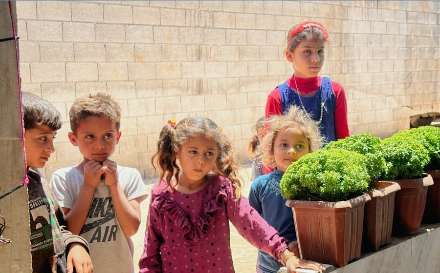 Niñas y niños alrededor de una mesa con verduras recién cosechadas